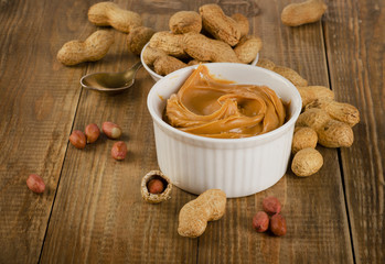 Peanut butter with peanuts on a rustic wooden table.