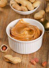 Peanut butter in  white bowl with peanuts.