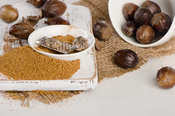 Organic ground  Nutmeg on  a white wooden cutting board.