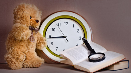 toy - a bear cub before clock near the book   © vladz_2009