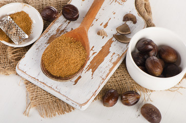 Raw Organic ground  Nutmeg on  white wooden cutting board.
