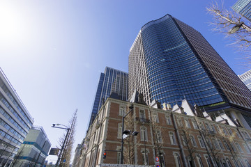 Naklejka premium 丸の内 高層ビル街 レンガの三菱第1号館前あたり 太陽 レンズフレア