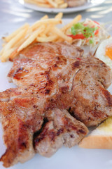 Grilled steaks, French fries, fried egg and vegetables