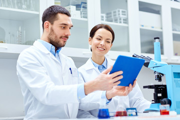 scientists with tablet pc and microscope in lab