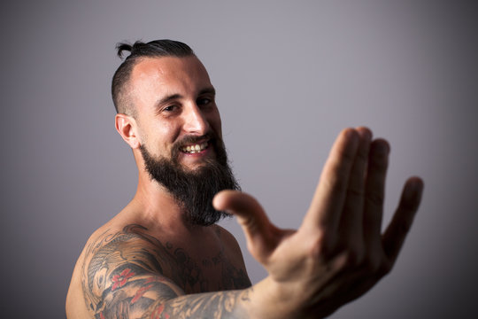 Joven hipster tatuado con mano alzada