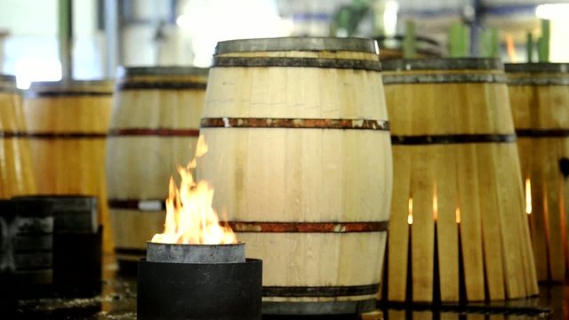 Fireplace in front of wood barrels. Artisan in skirt crossing.