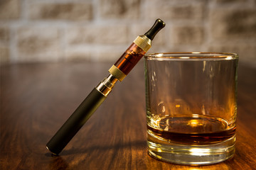 Stillleben mit elektrischer Zigarette und Glas Bourbon