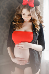 Happy pregnant woman with a large red-and-black bow.