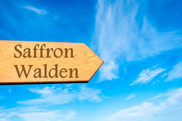 Wooden arrow sign pointing destination SAFFRON WALDEN, ENGLAND