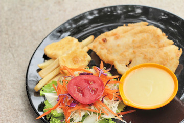 fish steaks and vegetable salad with french fries.