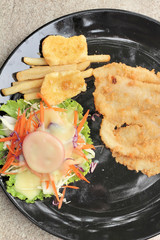 fish steaks and vegetable salad with french fries.