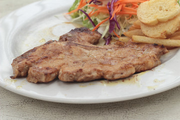 steaks and vegetable salad with french fries.