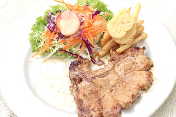 steaks and vegetable salad with french fries.