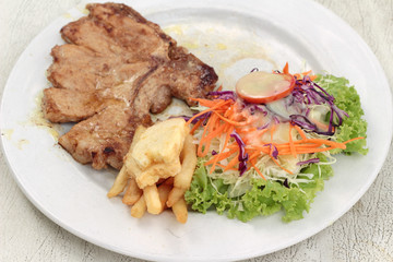 steaks and vegetable salad with french fries.
