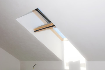 Opened roof window dormer with white wall in new attic room