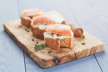 small sandwiches with soft cheese and salmon on wood table