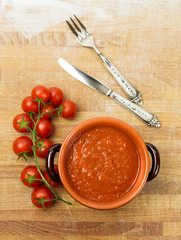 tomato sauce inside earthenware pan and cherry tometoes