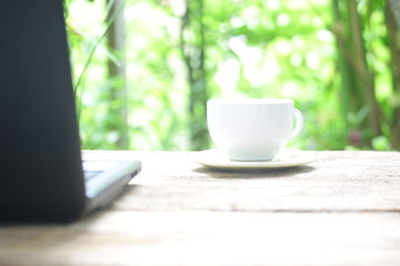 Coffee cup and laptop on wood table  