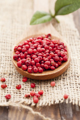 red peppercorns in wooden spoon