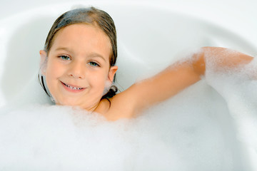 Girl playing with water and foam in a  bathtub
