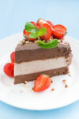 piece of chocolate cake of three layers with fresh strawberries