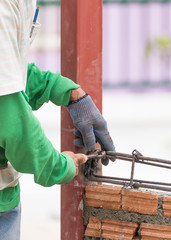 Workers using steel wire and pincers rebar before concrete is po