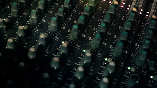 Close-up panning shot of EQ Knobs on a mixing console desk