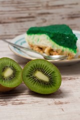 Fototapeta na wymiar Kiwi fruit cut in half in front of green slice of cake