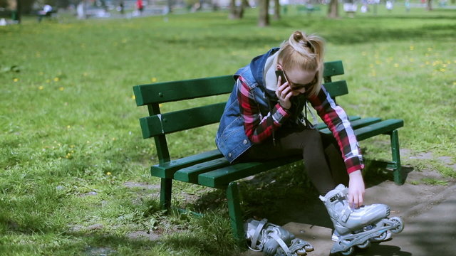 Girl wearing rollerblades and chatting on cellphone in park
