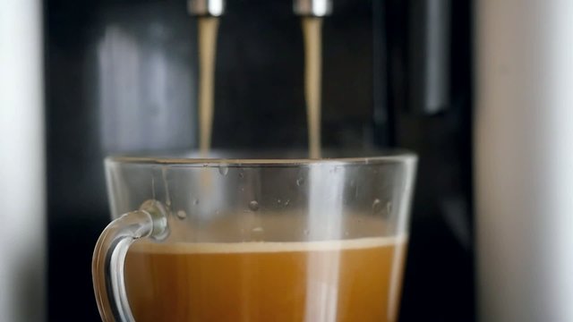 coffe dispenser with cup of coffee. Slowmotion pour