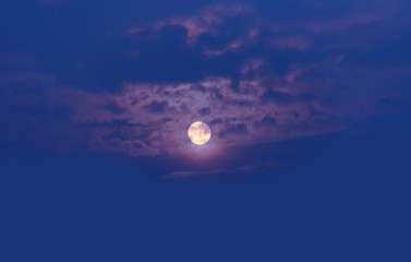  The setting sun on the dark blue sky hiding behind the clouds. 