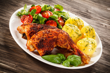 Barbecued chicken legs with boiled potatoes and vegetables 