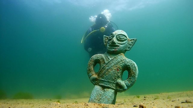 Diver with a metal detector  found ancient sculpture