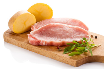 Raw pork chops on cutting board on white background