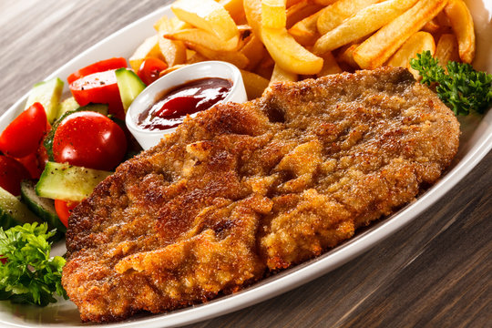 Fried pork chop, French fries and vegetable salad 