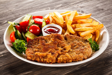 Fried pork chop, French fries and vegetable salad 