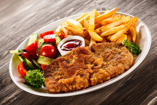 Fried pork chop, French fries and vegetable salad 