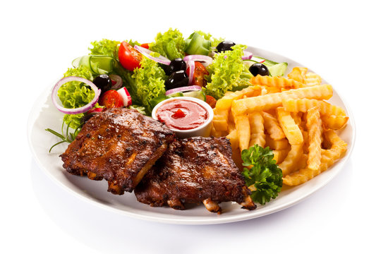 Grilled ribs, French fries and vegetables on white background