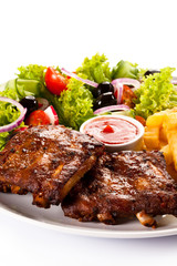 Grilled ribs, French fries and vegetables on white background