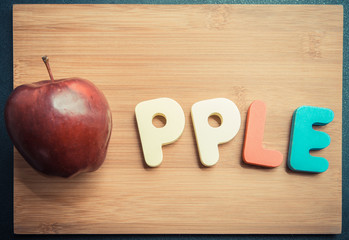 Apple with wooden word on chopping block