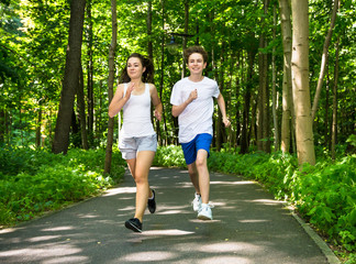 Teenage girl and boy running in park