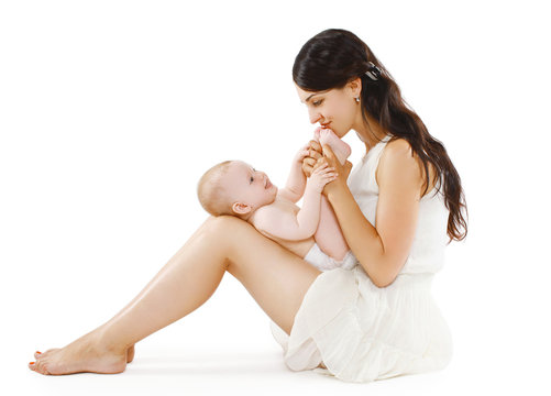 Happy loving  young mother kissing feet her baby