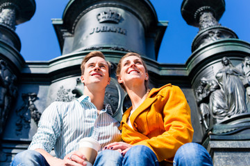 Paar sitzt in Dresden an Denkmal auf Theaterplatz