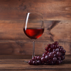 Red wine in glass with grape on wood