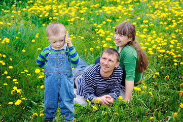 Young family walking on the meadow with yellow flowers in spring