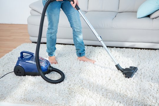 Woman Using Vacuum Cleaner On Carpet