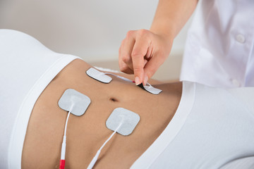 Therapist Placing Electrodes On Woman's Stomach - obrazy, fototapety, plakaty