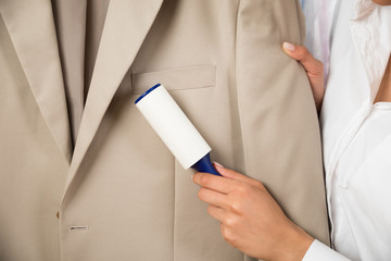 Woman Cleaning Coat With Adhesive Roller