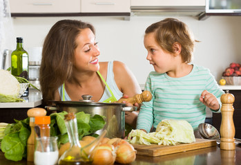 Woman with little girl cooking at home