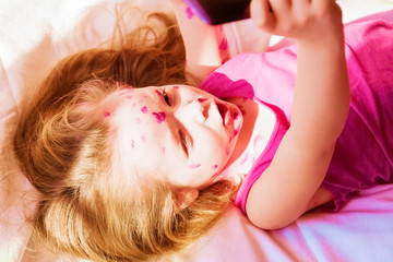 Ill little girl playing on a tablet